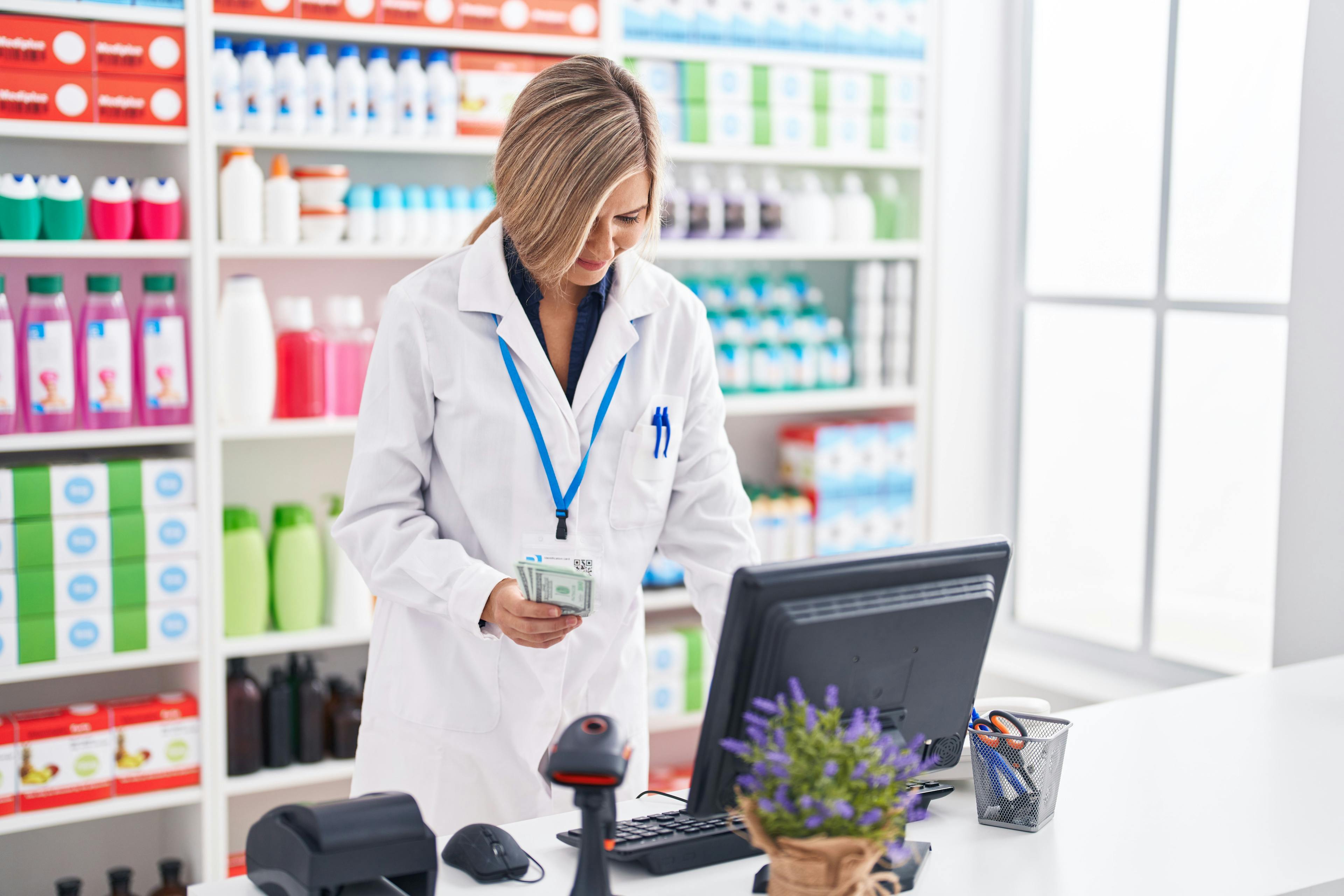 Pharmacist putting money into cash register / Krakenimages - stock.adobe.com