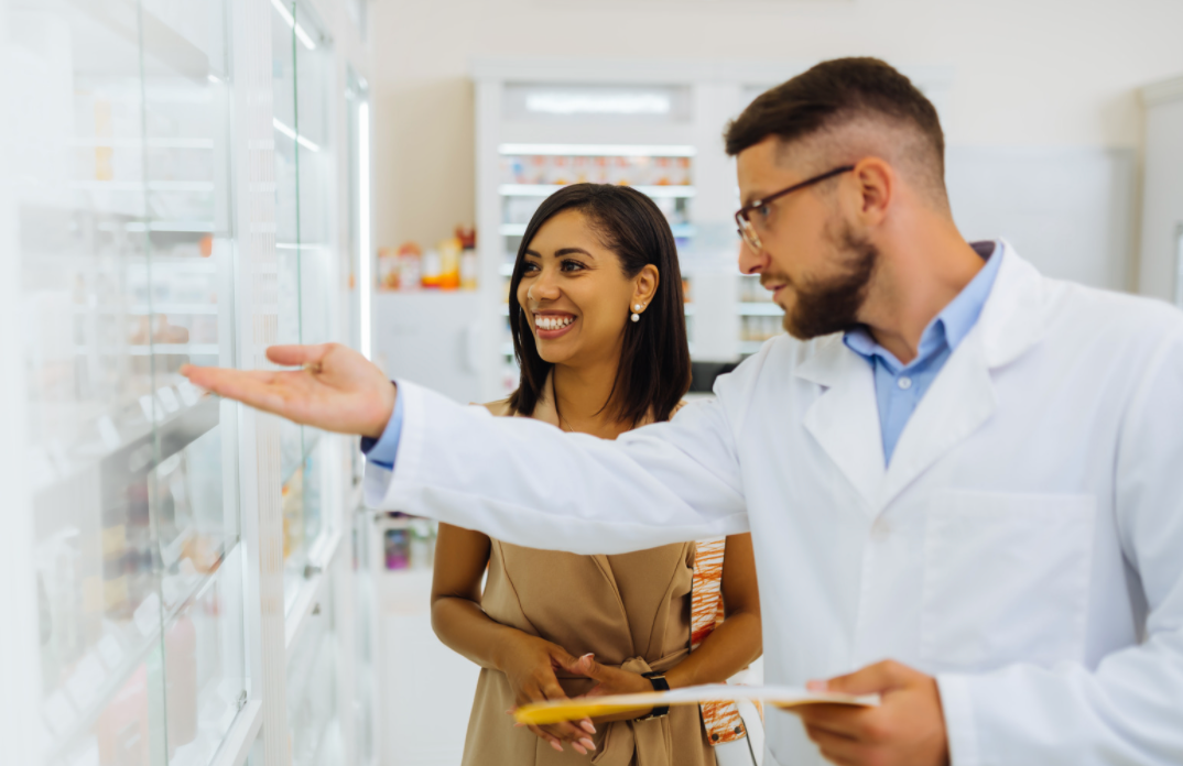 woman with pharmacist looking at drugs on shelf