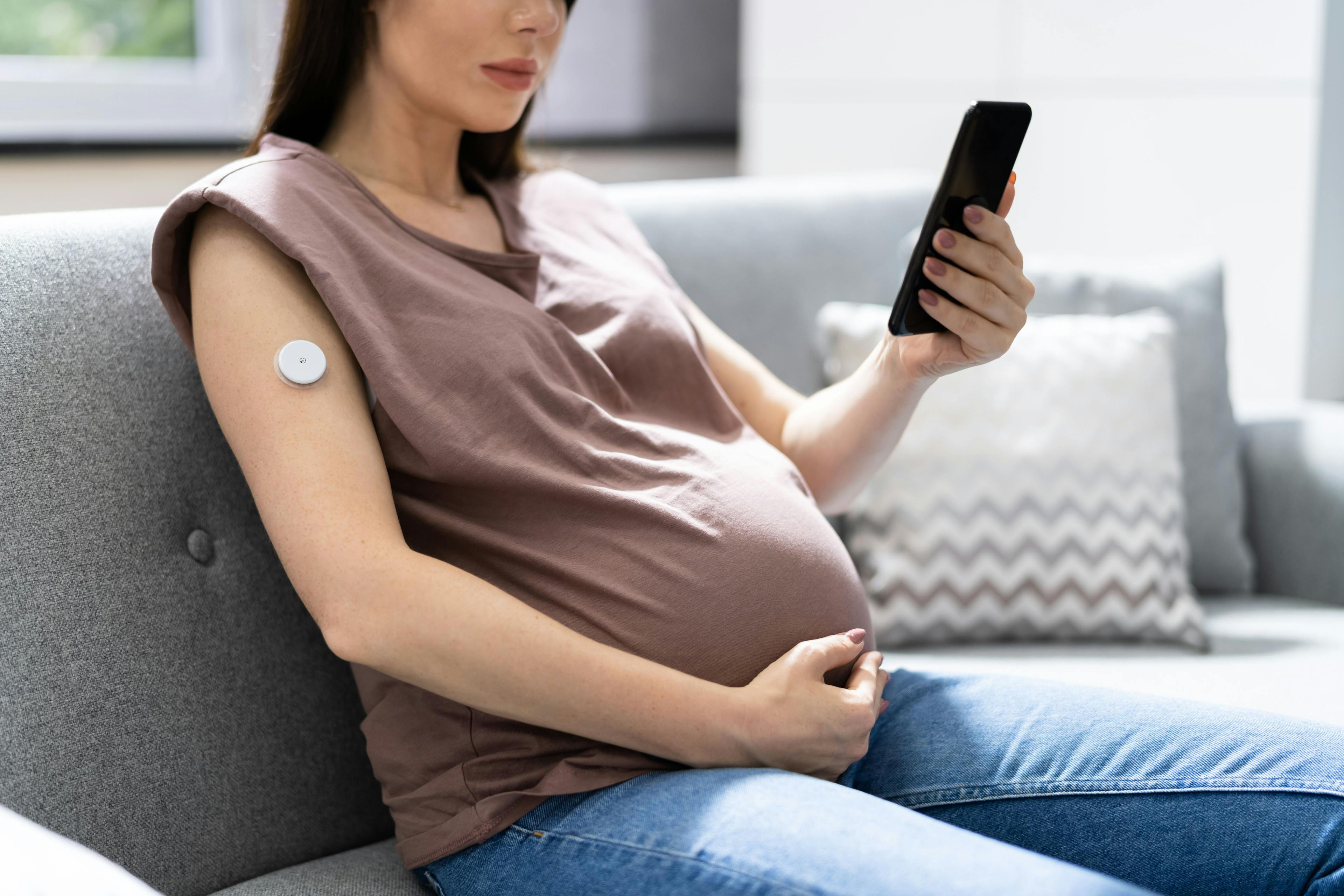 Pregnant woman using continuous glucose monitor / Andrey Popov - stock.adobe.com