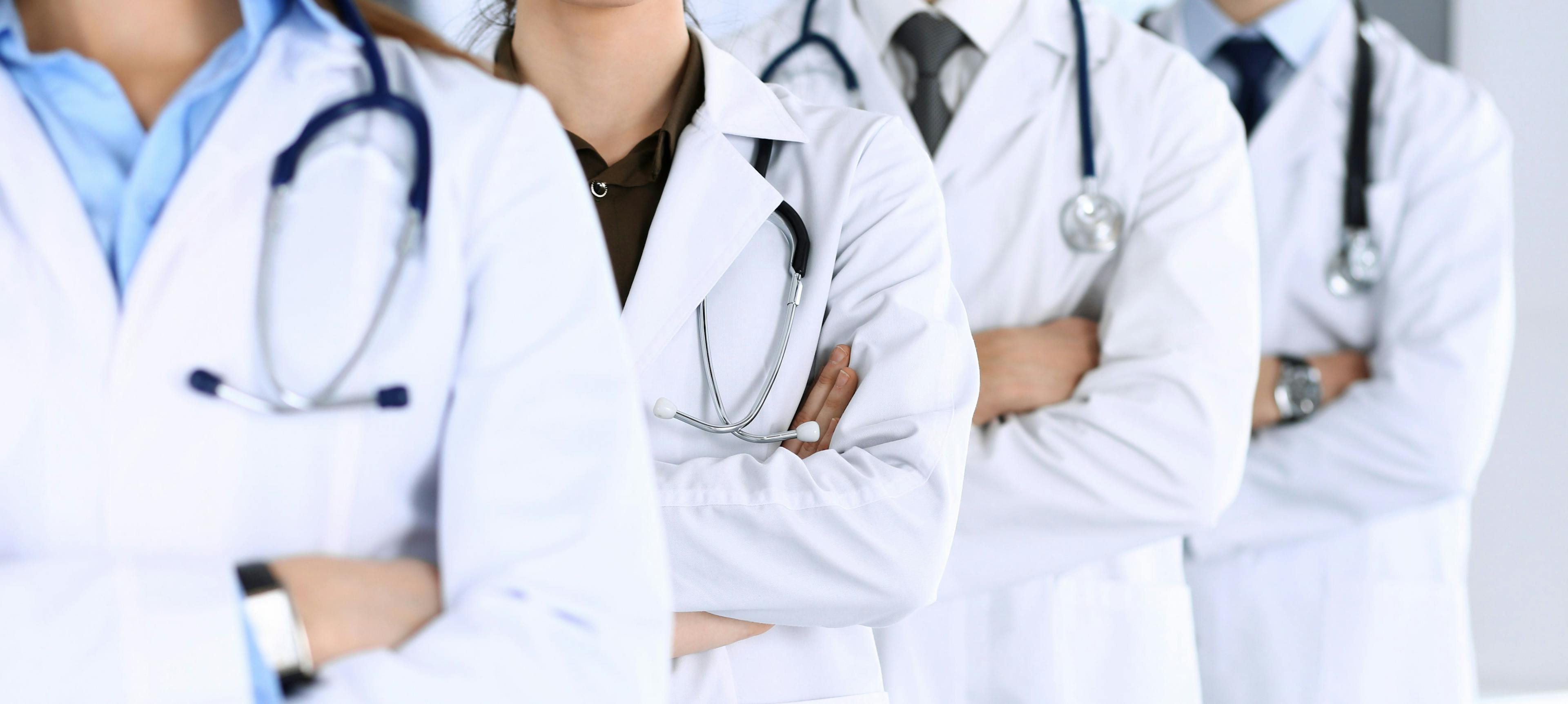 row of doctors standing with arms crossed all in white coats with stethoscopes