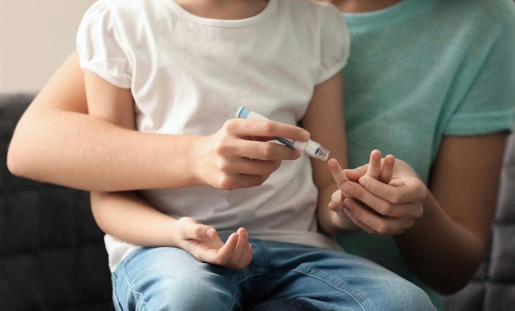 diabetic child testing blood glucose levels with lancet 
