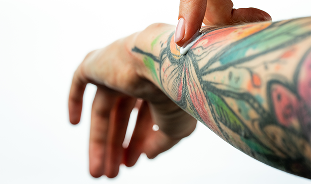 man applying cream to tattoo